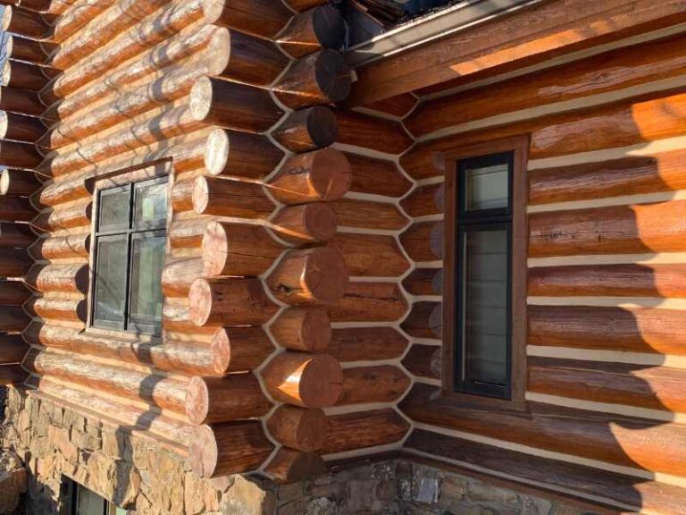 Fresh white chinking lines between stained round logs on a Jackson Hole log home