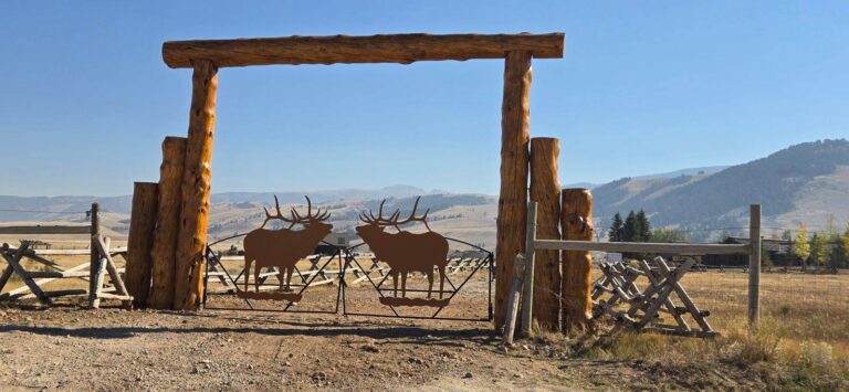 New log ranch archway with an elk silhouette panel, stained to match the house, Jackson Wyoming
